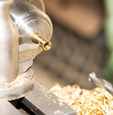 A brass stone setting being turned on a lathe