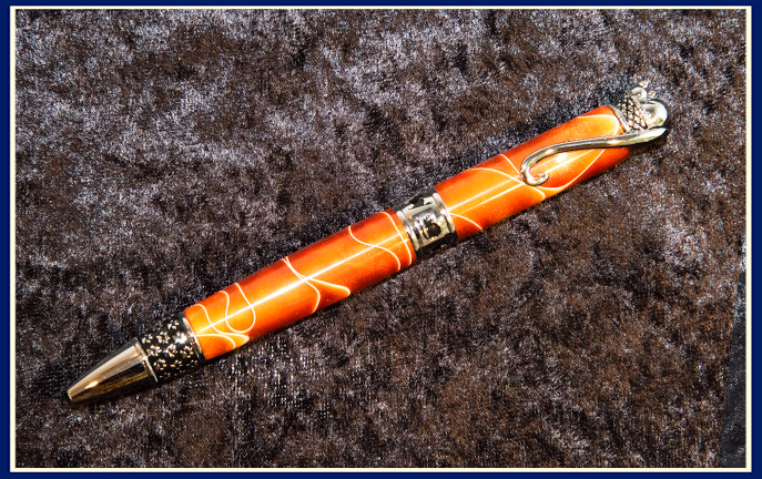 A hand turned pen with a sleeping cat on the end in orange
